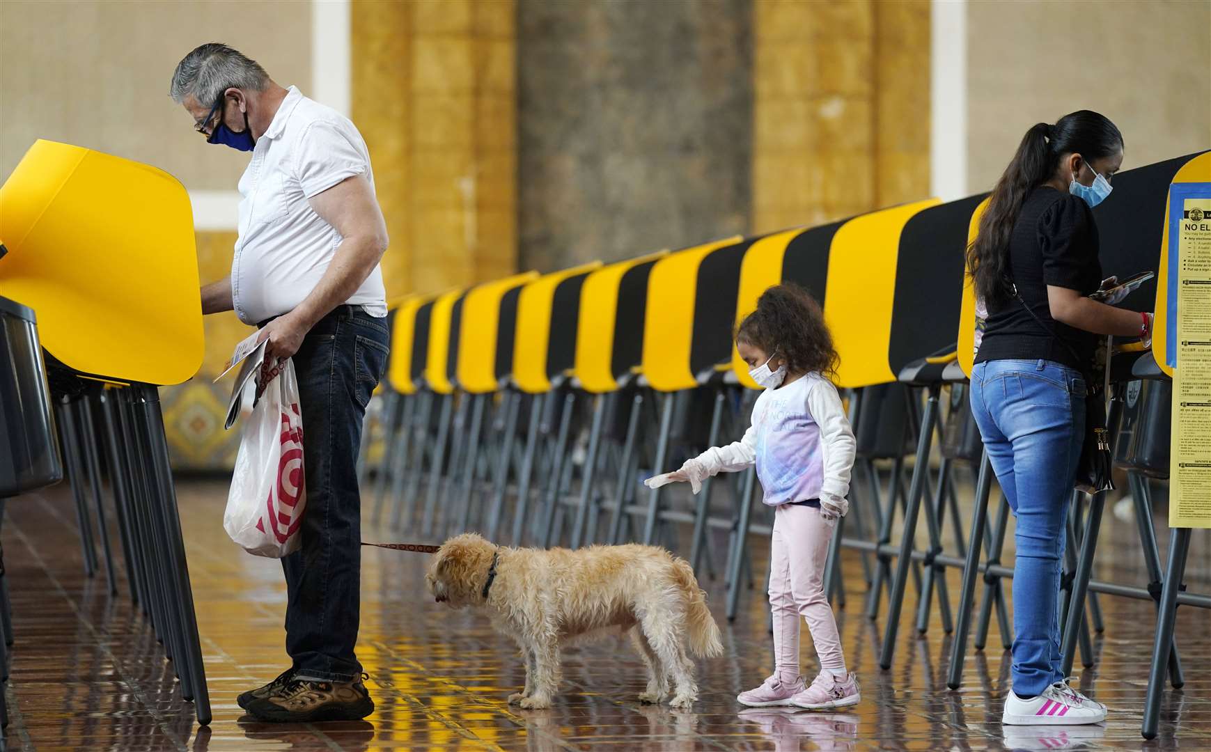 At one Los Angeles polling station, a four-year-old girl tried to get the attention of another voter’s dog while her mother cast her vote (AP Photo/Chris Pizzello)