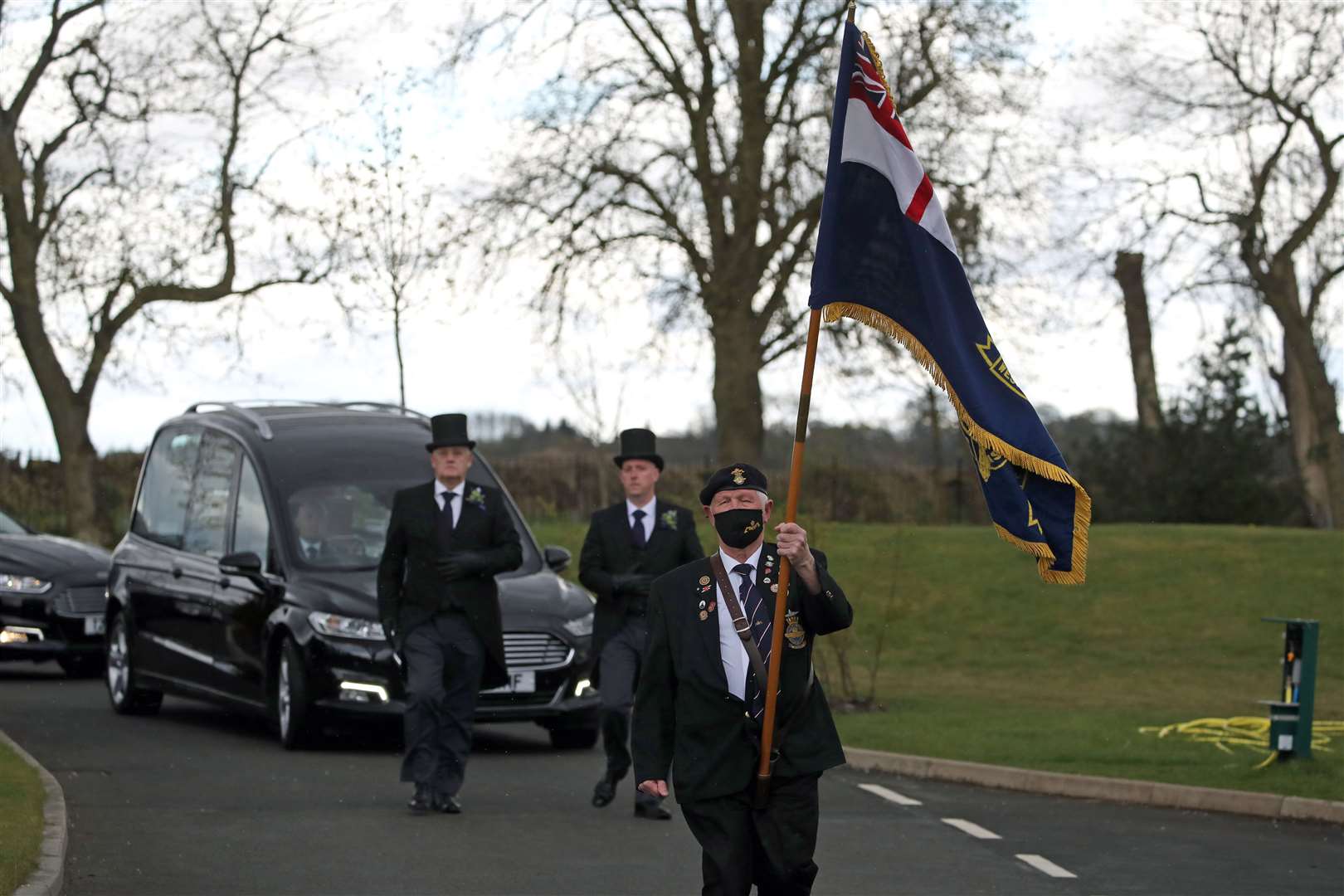 A retired submariner walks in front of the cortege as it arrives at Stirling Crematorium (Andrew Milligan/PA)