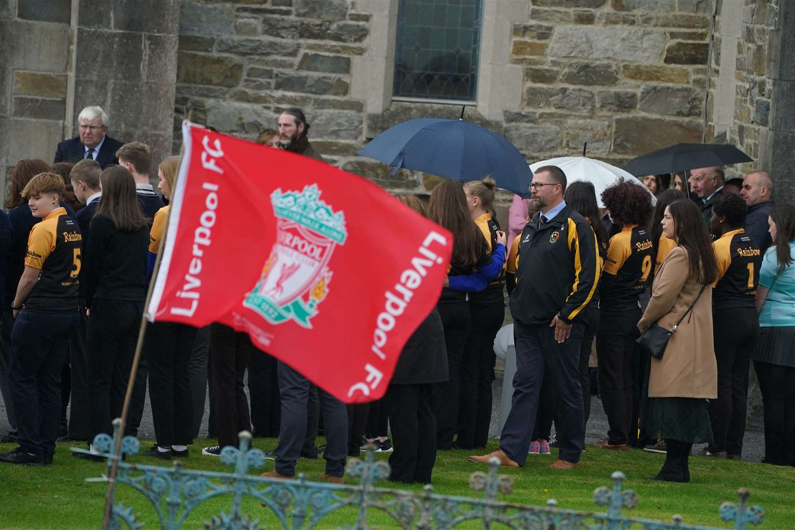 A Liverpool FC flag is flown as members of Letterkenny Rugby Club join mourners outside St Mary’s Church for the funeral Mass of Leona Harper (Brian Lawless/PA)