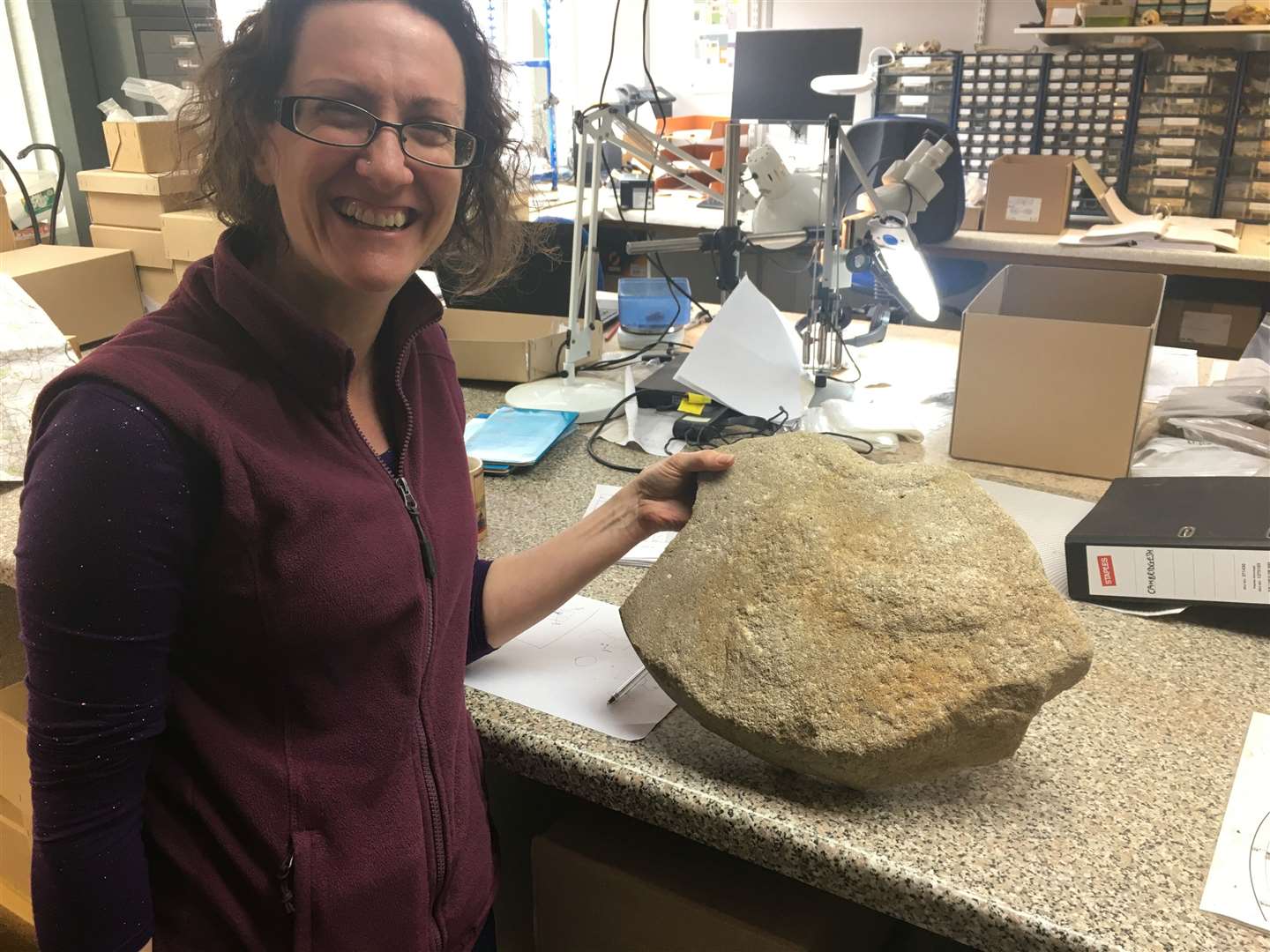 Dr Ruth Shaffrey of Oxford Archaeology with the rare Roman millstone. (Highways England/ PA)