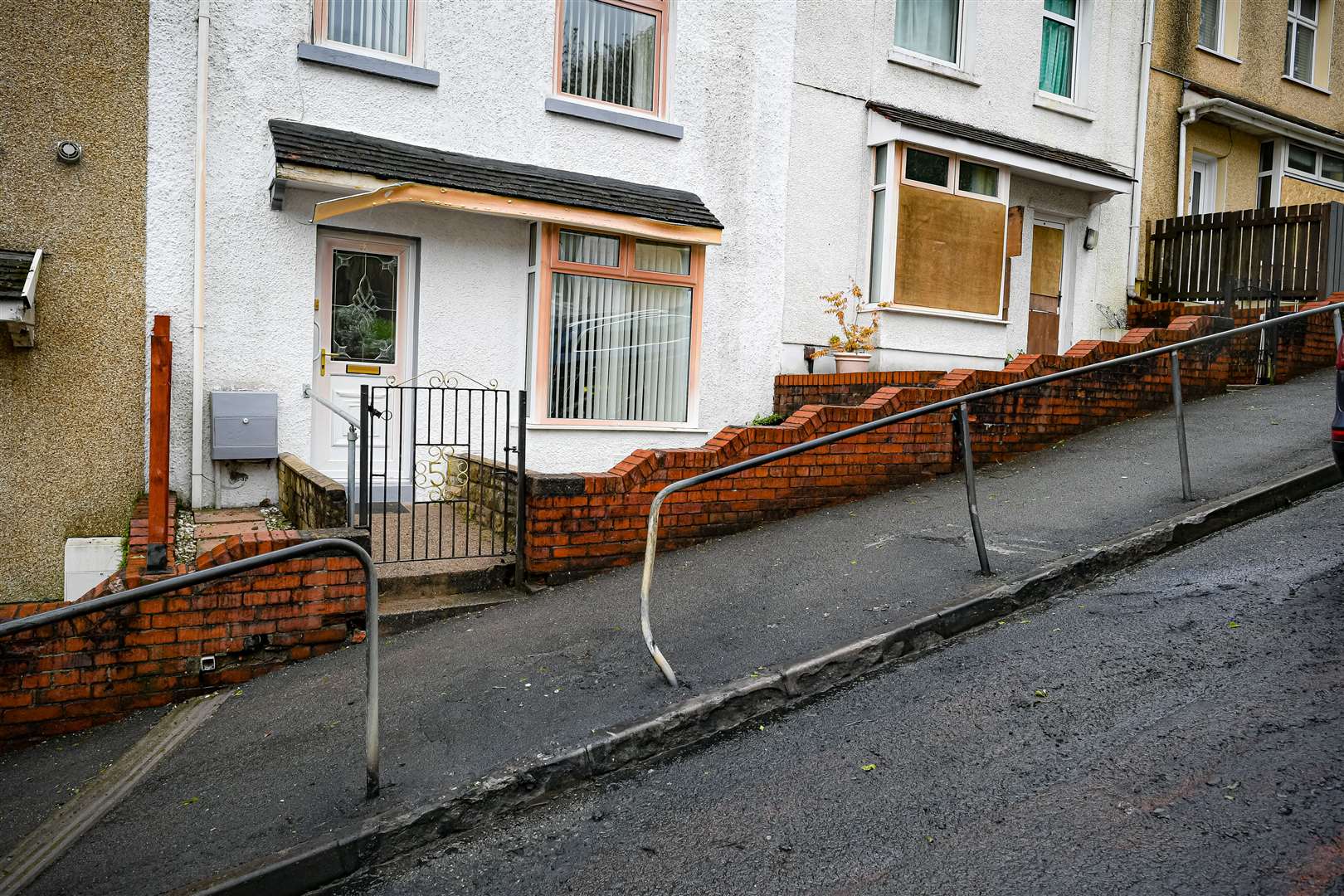 Blackened tarmac, damaged railings and boarded up houses at the top of Waun Wen Road (Ben Birchall/PA)