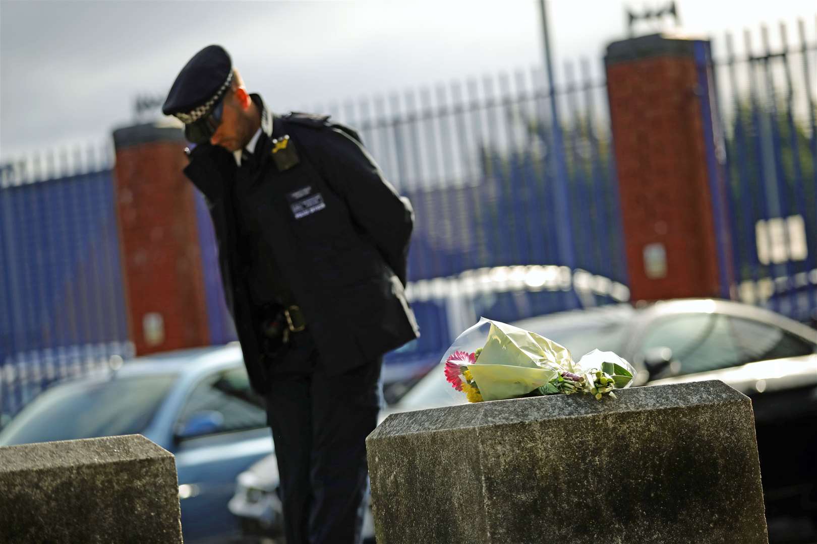 A police officer beside flowers left outside Croydon Custody Centre in south London (Aaron Chown/PA)