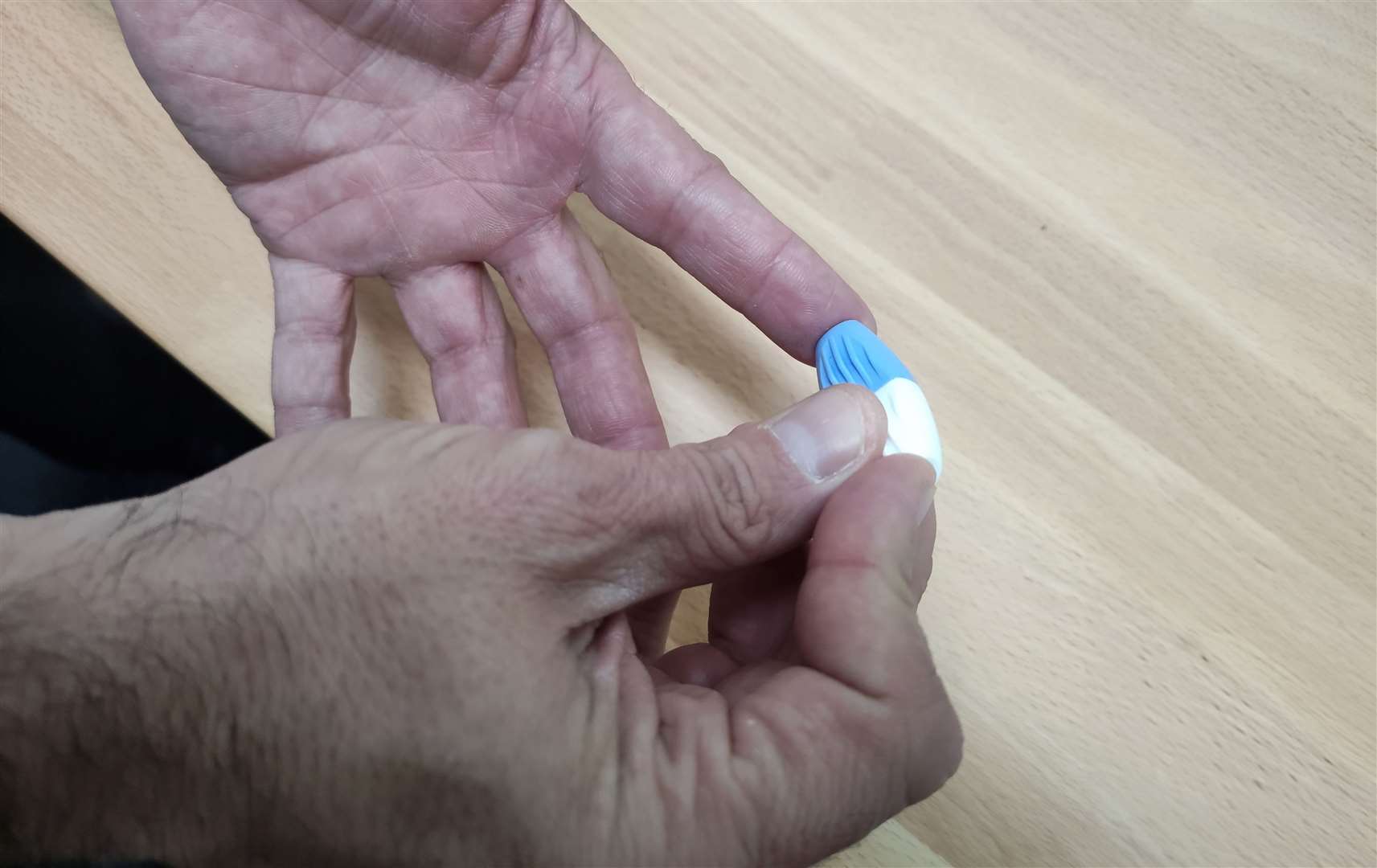 A user performs a simple finger prick to take a blood sample for hepatitis C testing.