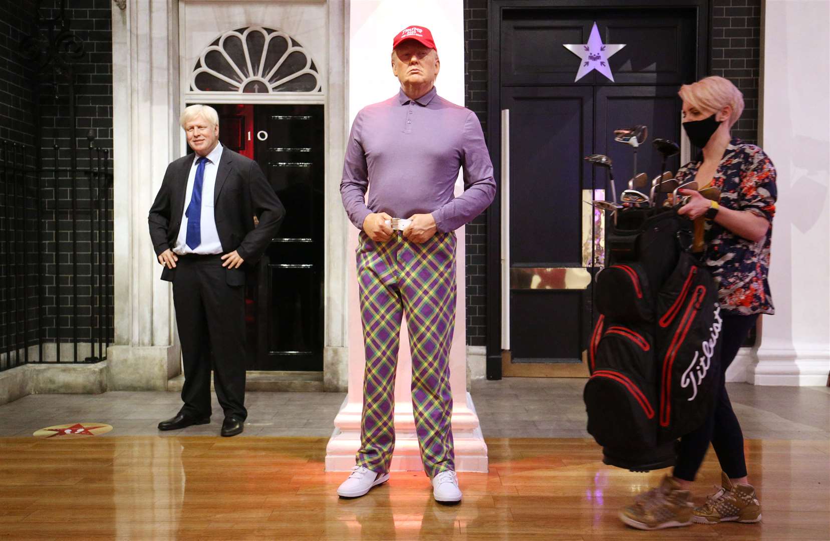 A member of the Madame Tussauds studios team places a set of golf clubs next to a wax figure of Donald Trump which has been re-dressed in golf wear following his defeat (Jonathan Brady/PA)