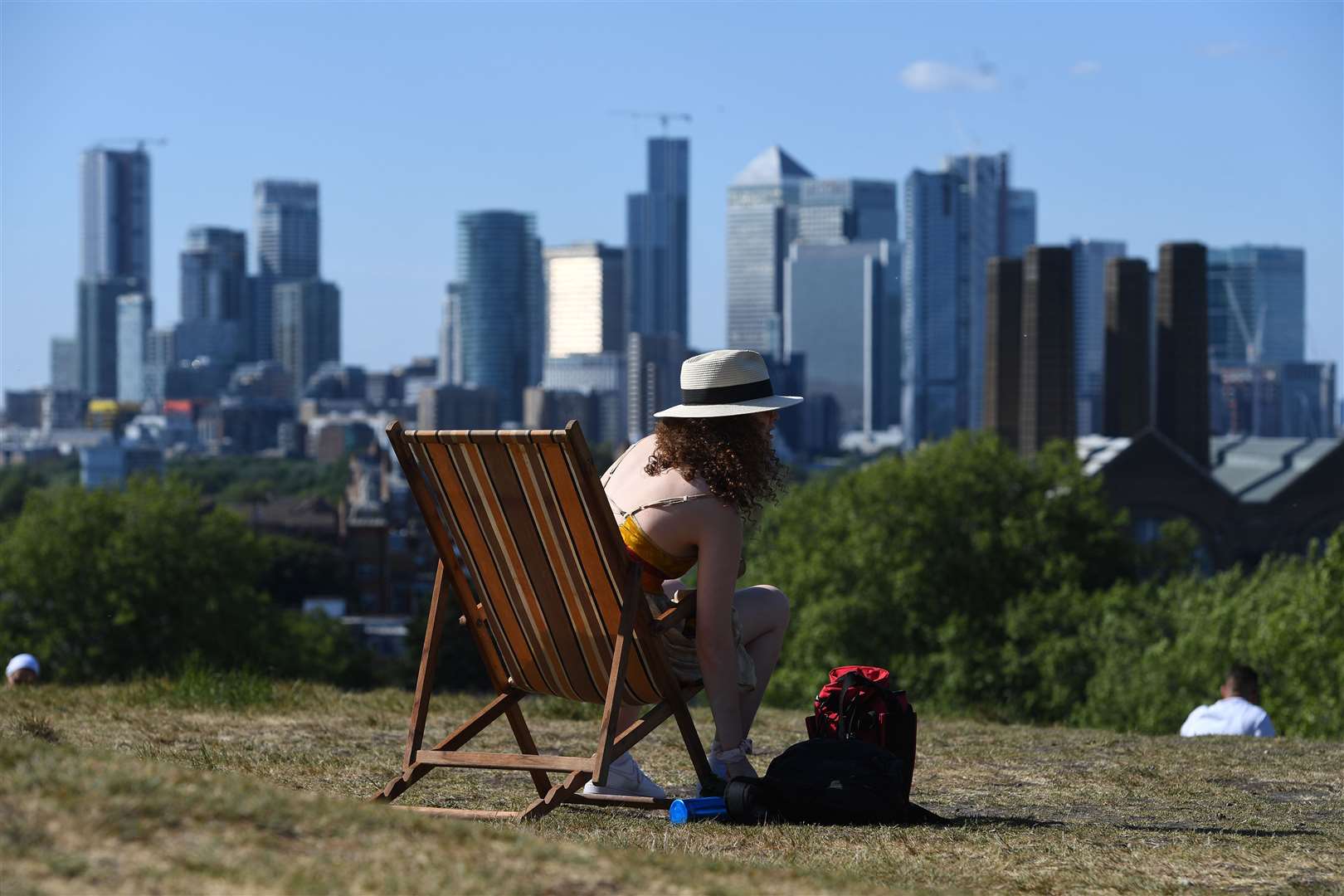 A woman sunbathes on a deck chair in Greenwich Park, London (Kirsty O’Connor/PA)