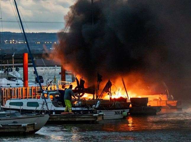 Firefighters and boat owners desperately try to put the flames out of a vessel which exploded at Queenborough marina. Picture: Henry Slack