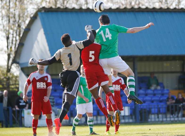 Ashford United's Gary Mickelborough climbs above Beckenham defender Nathan Paul (5) and goalkeeper Rilwan Anibaba