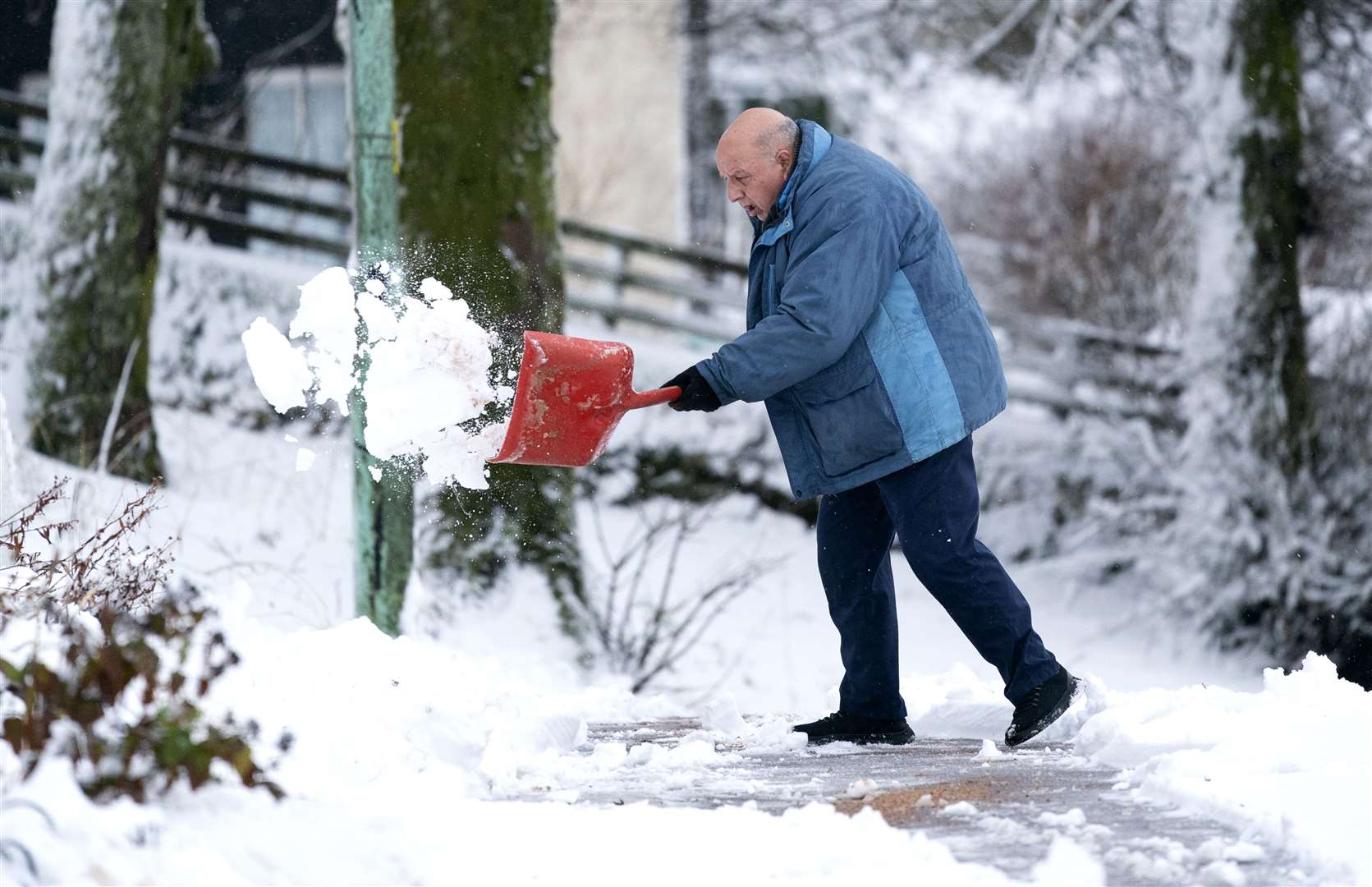 A man clears snow away in Leadhills, South Lanarkshire as Storm Barra hits the UK (Jane Barlow/PA)