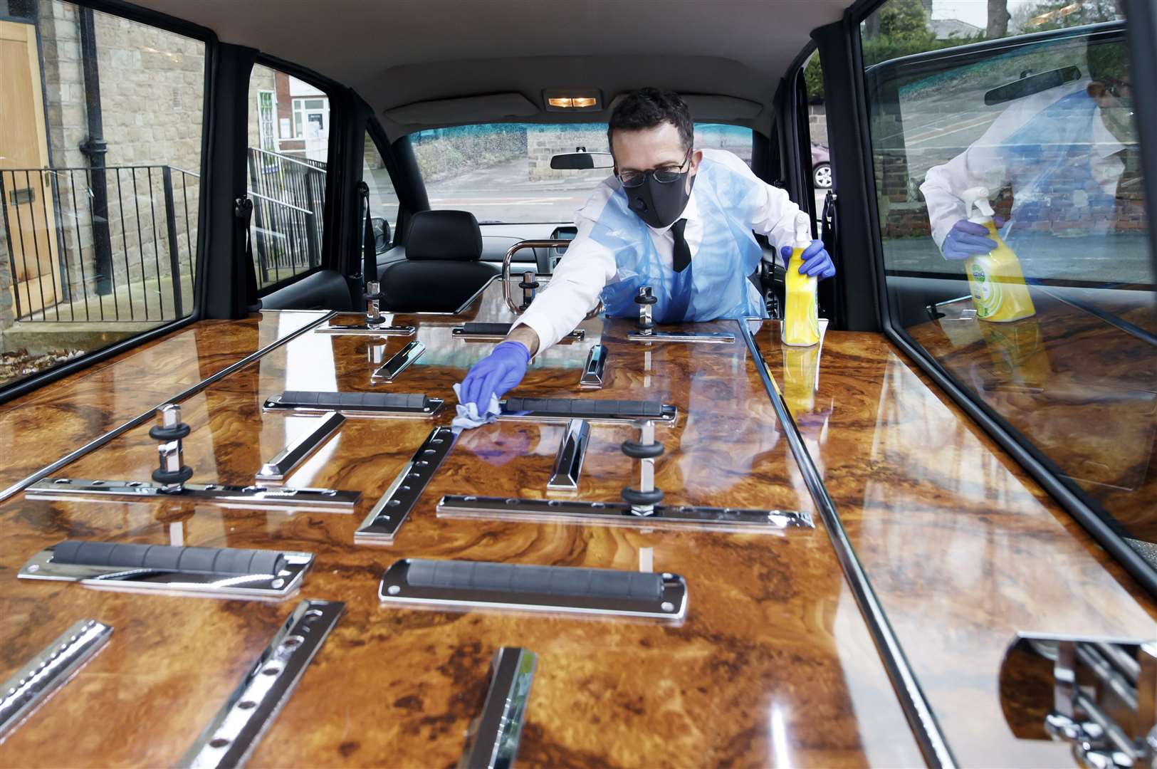 Funeral director Andrew Atkins wears PPE as he disinfects a hearse at Full Circle Funerals (Danny Lawson/PA)