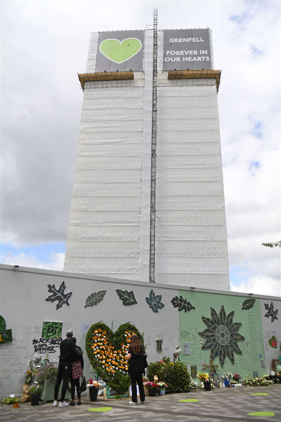 People at the Grenfell Memorial Community Mosaic at the base of the tower block in London (Kirsty O’Connor/PA)