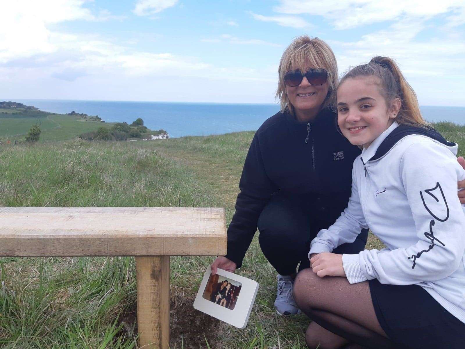 Tracy Squire and granddaughter Keira place family photos in the ground