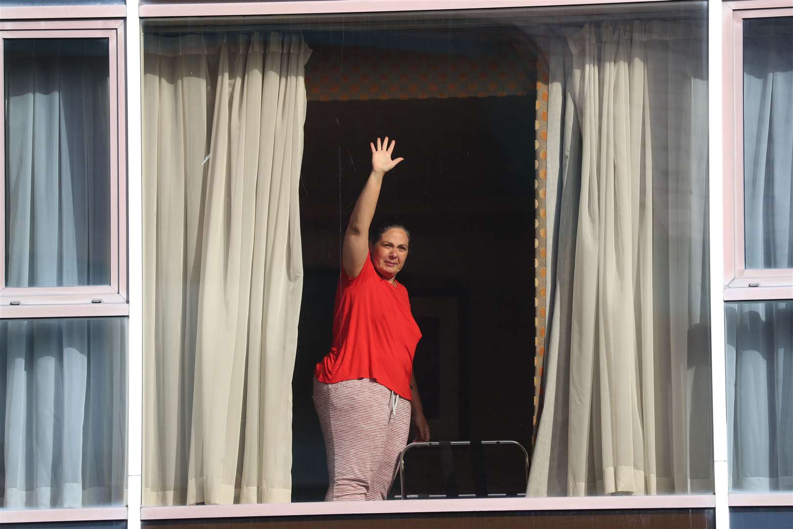 A hotel guest waves to members of the media from the window of Radisson Blu Edwardian Hotel (Jonathan Brady/PA)