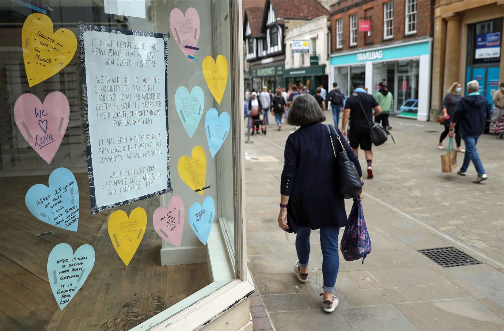 People walk past a closed-down Laura Ashley shop, with messages from staff and customers in the shop window, on the High Street in Winchester, Hampshire (Andrew Matthews/PA)