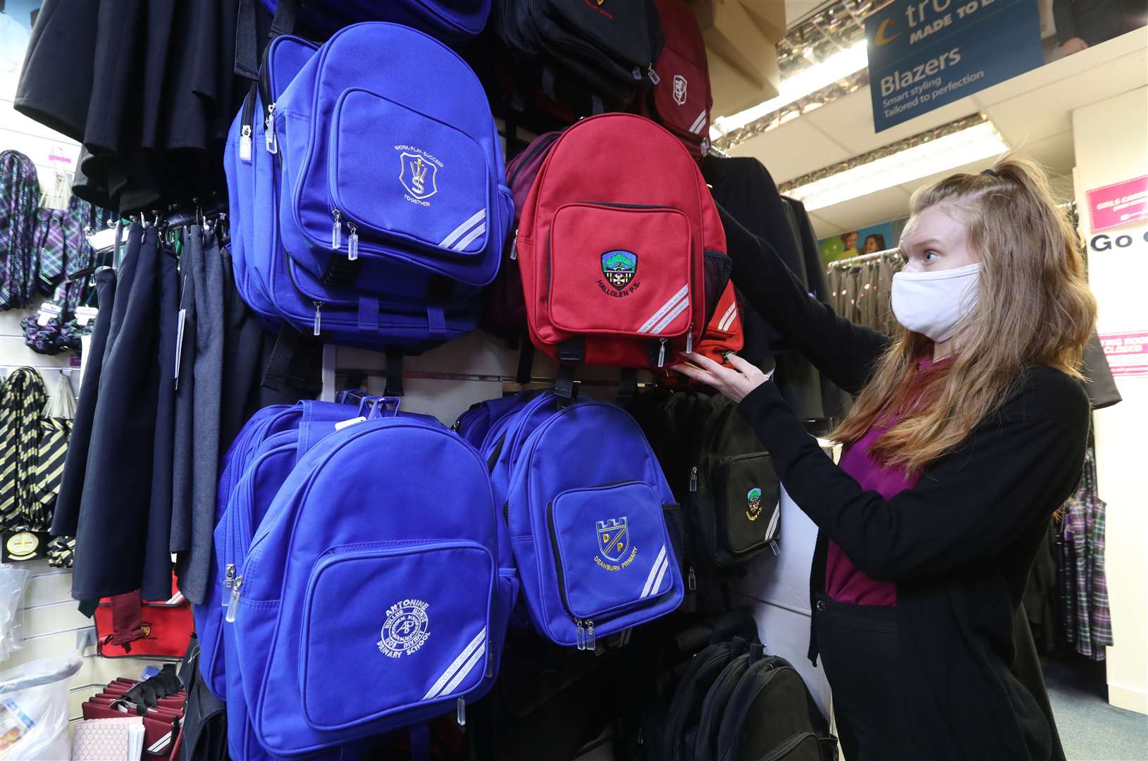 Caitlin Morrow from BE Schoolwear in Falkirk hangs school bags in their store (Andrew Milligan/PA)