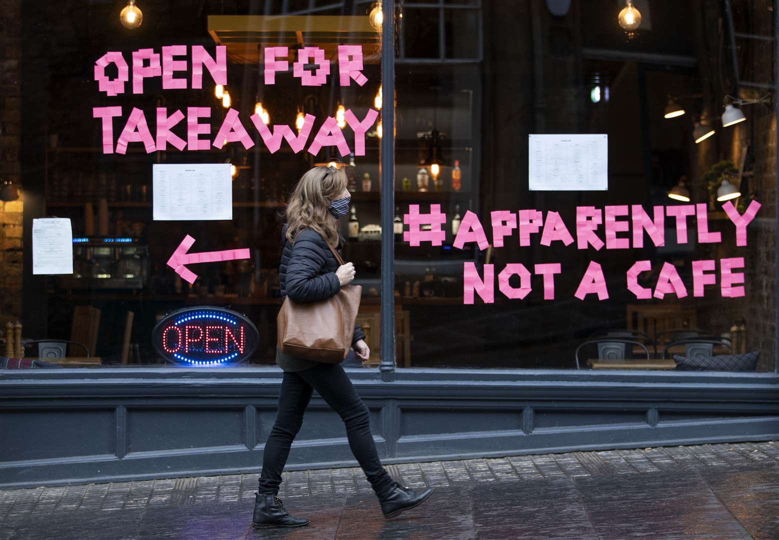 A woman walks past Scran cafe in Edinburgh’s Cockburn Street after a range of new restrictions to combat the rise in coronavirus cases came into place in Scotland (Jane Barlow/PA)