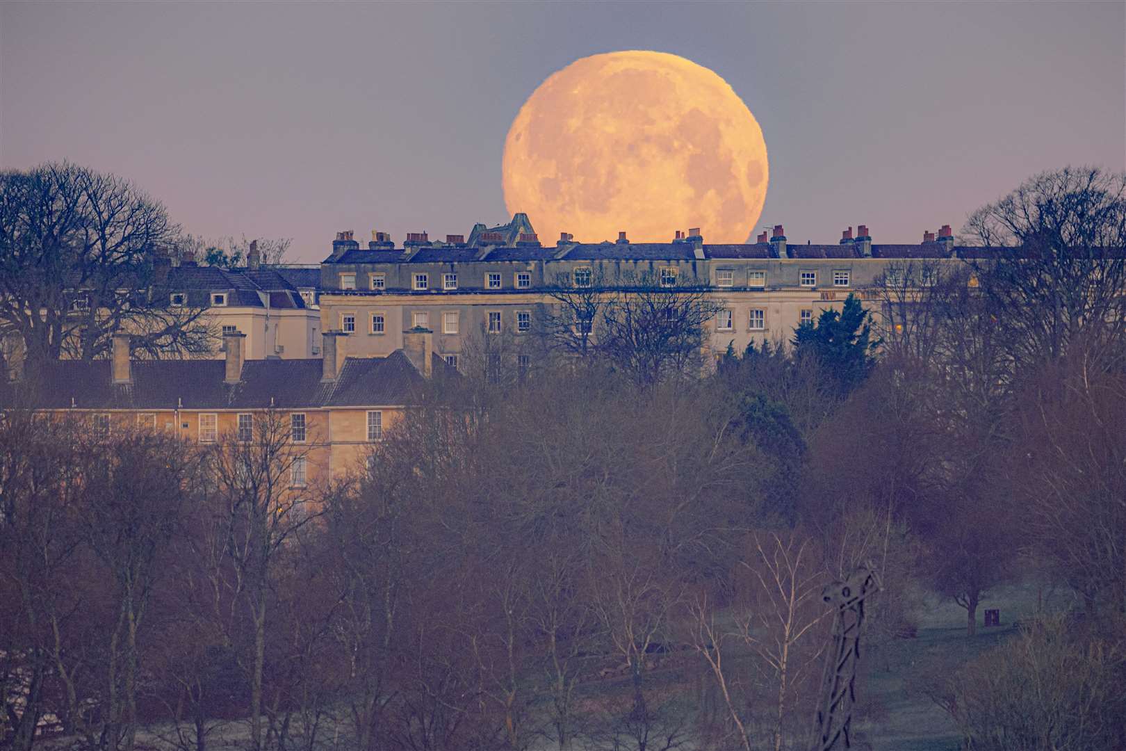 The moon appears behind houses in Bristol (Ben Birchall/PA)