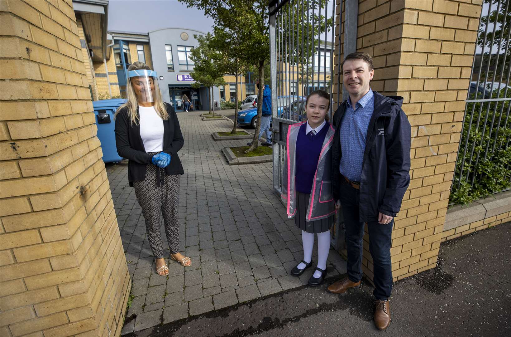 Brendan Gallagher dropping off his 11-year-old daughter Abigail at St Clare’s Primary School in Belfast with teacher Ashleigh Clarke greeting them wearing a protective visor and gloves (Liam McBurney/PA)