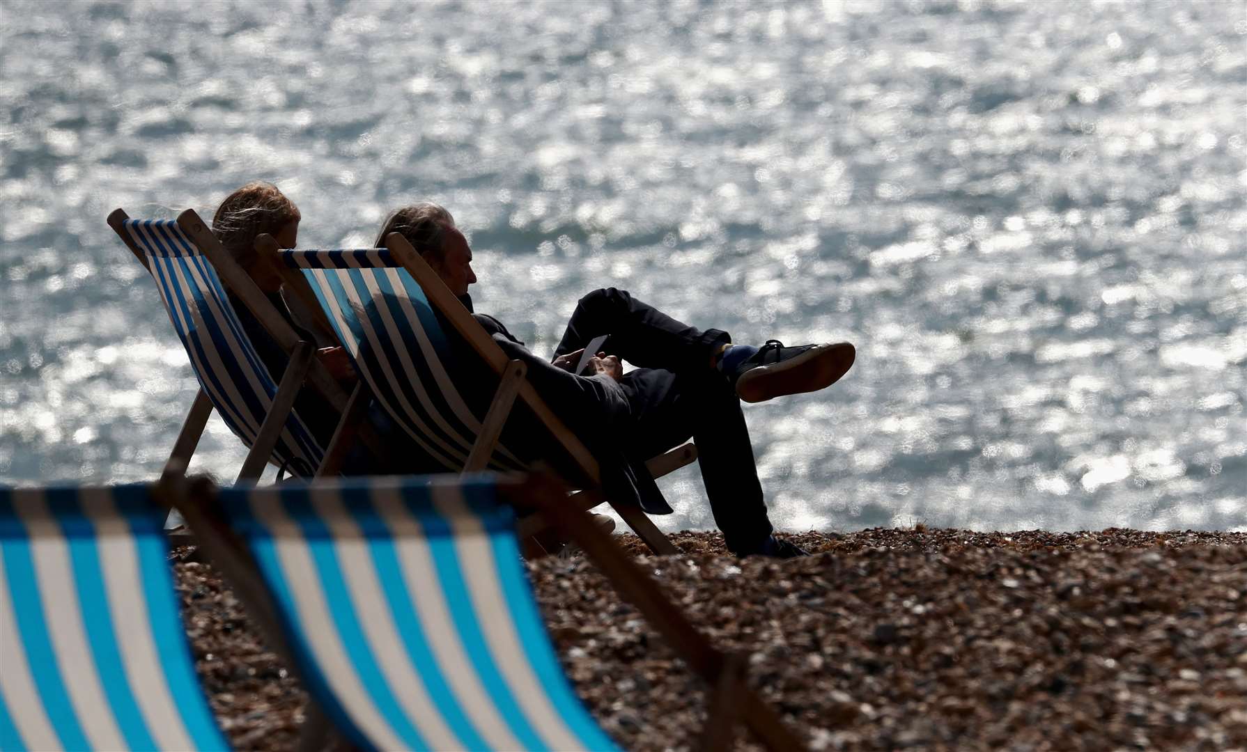 A couple enjoy the autumn sunshine on the beach in Brighton (Gareth Fuller/PA)