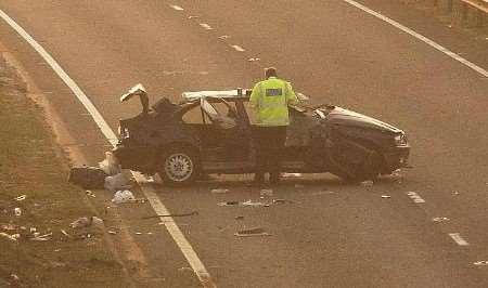 A police officer examines the wrecked car. Picture: CHRIS DAVEY