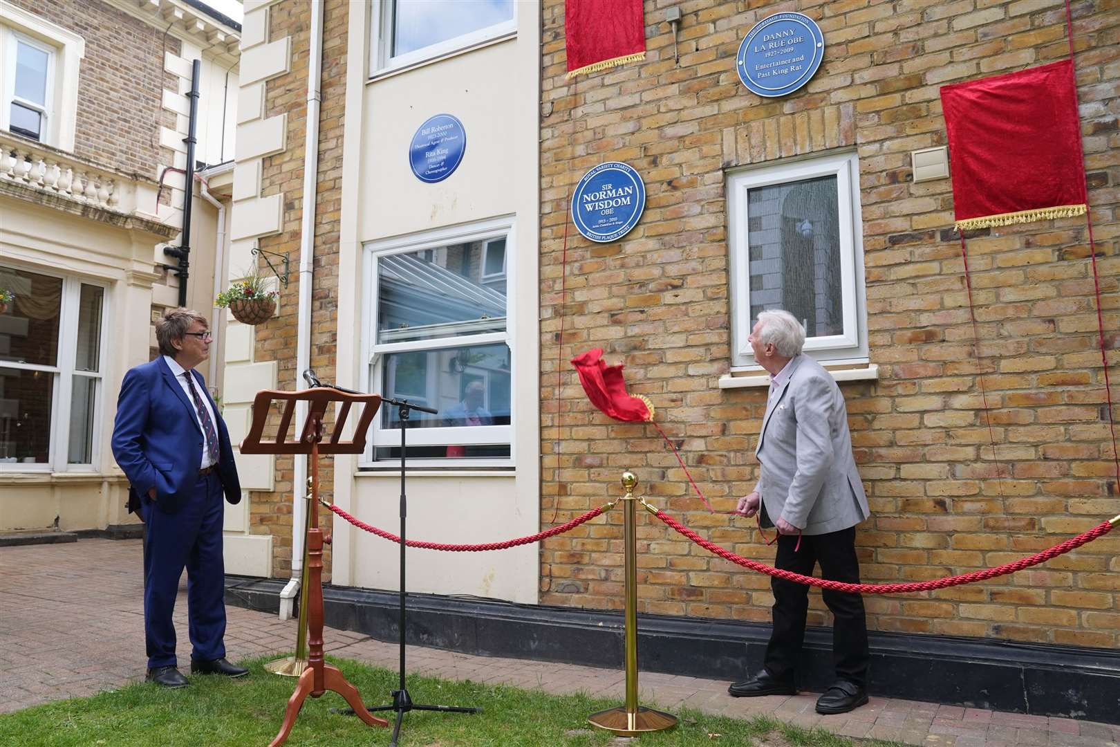 DJ Mike Read watches as Johnny Mans, who represented Sir Norman Wisdom, unveils a Blue Plaque in his name during a multi-plaque unveiling ceremony (Lucy North/PA)