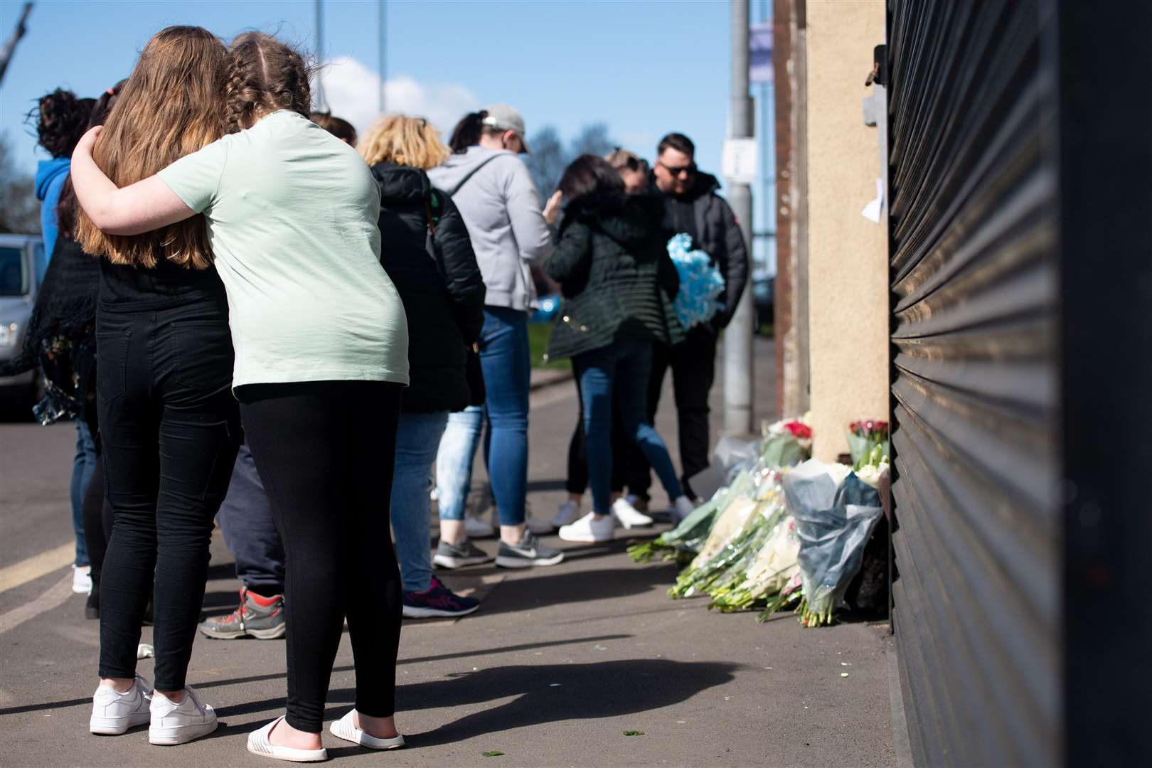 People embrace as flowers and tributes are left at the scene on High Street, Brownhills (Jacob King/PA)