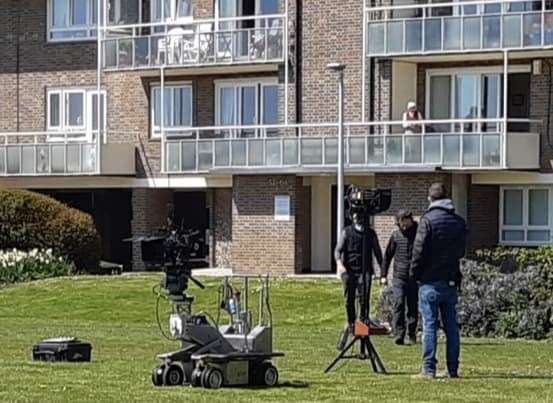 Camera crews set up for the filming of Pistols watched by residents in the Gateway Flats above