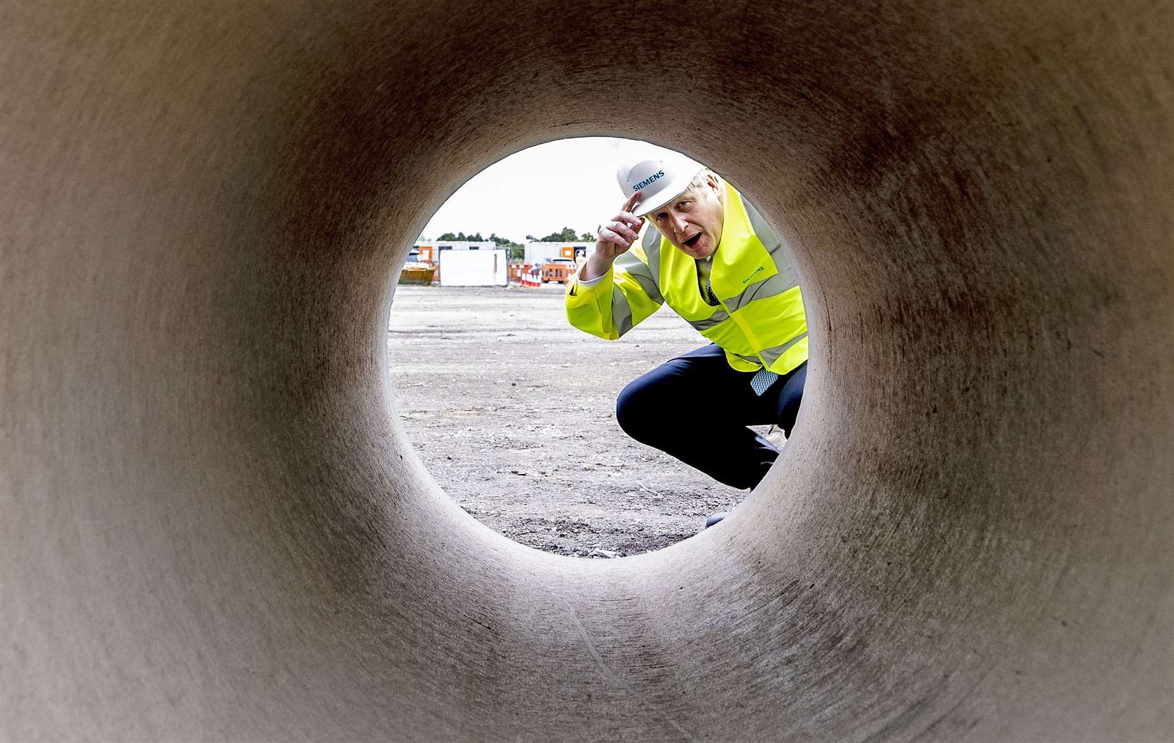 Prime Minister Boris Johnson looks through a large bore pipe during a visit to the Siemens Rail factory construction site in Goole (Peter Byrne/PA)