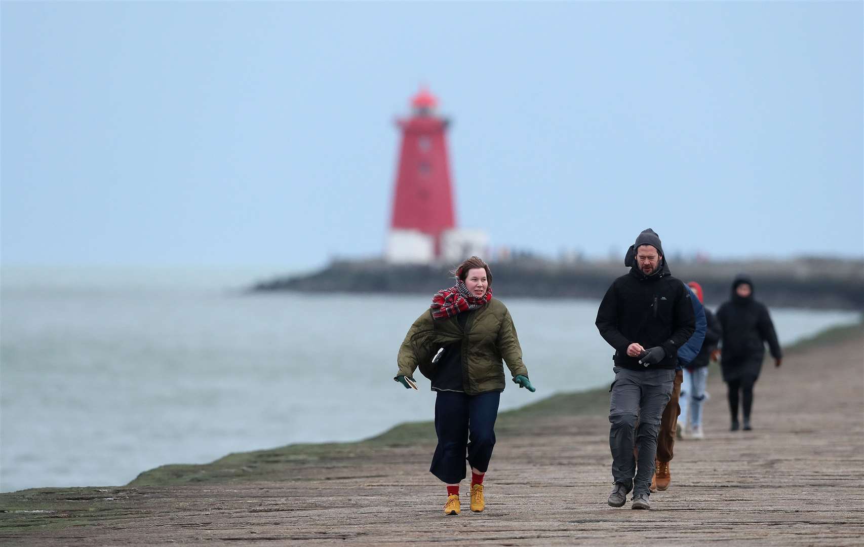 People walk on the Great South wall in Dublin as the wind picks up (Brian Lawless/PA)