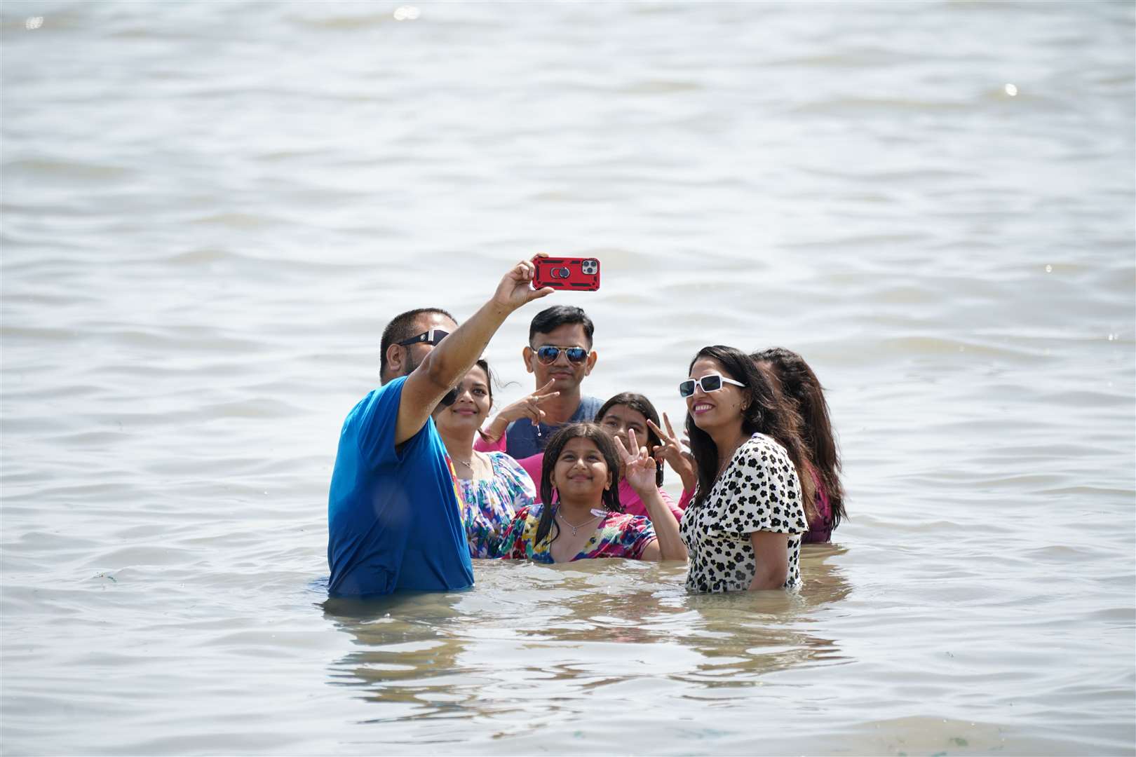 A man takes a family selfie in the water at Southend-on-Sea (Yui Mok/PA)