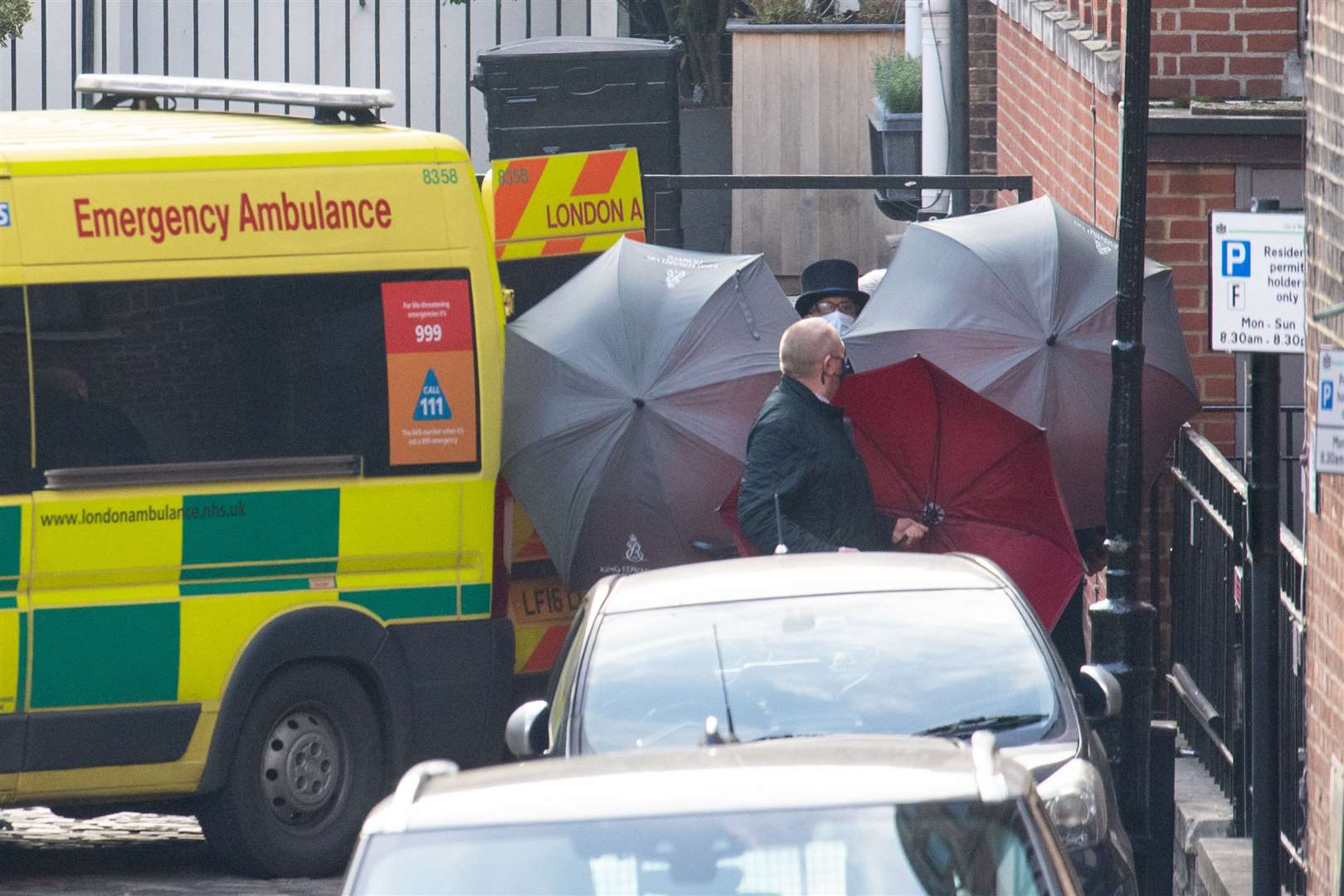 Staff shield the exit with umbrellas alongside an ambulance outside the rear of King Edward VII’s Hospital in London where the Duke of Edinburgh was admitted on the evening of Tuesday, February 16 (Dominic Lipinski/PA)