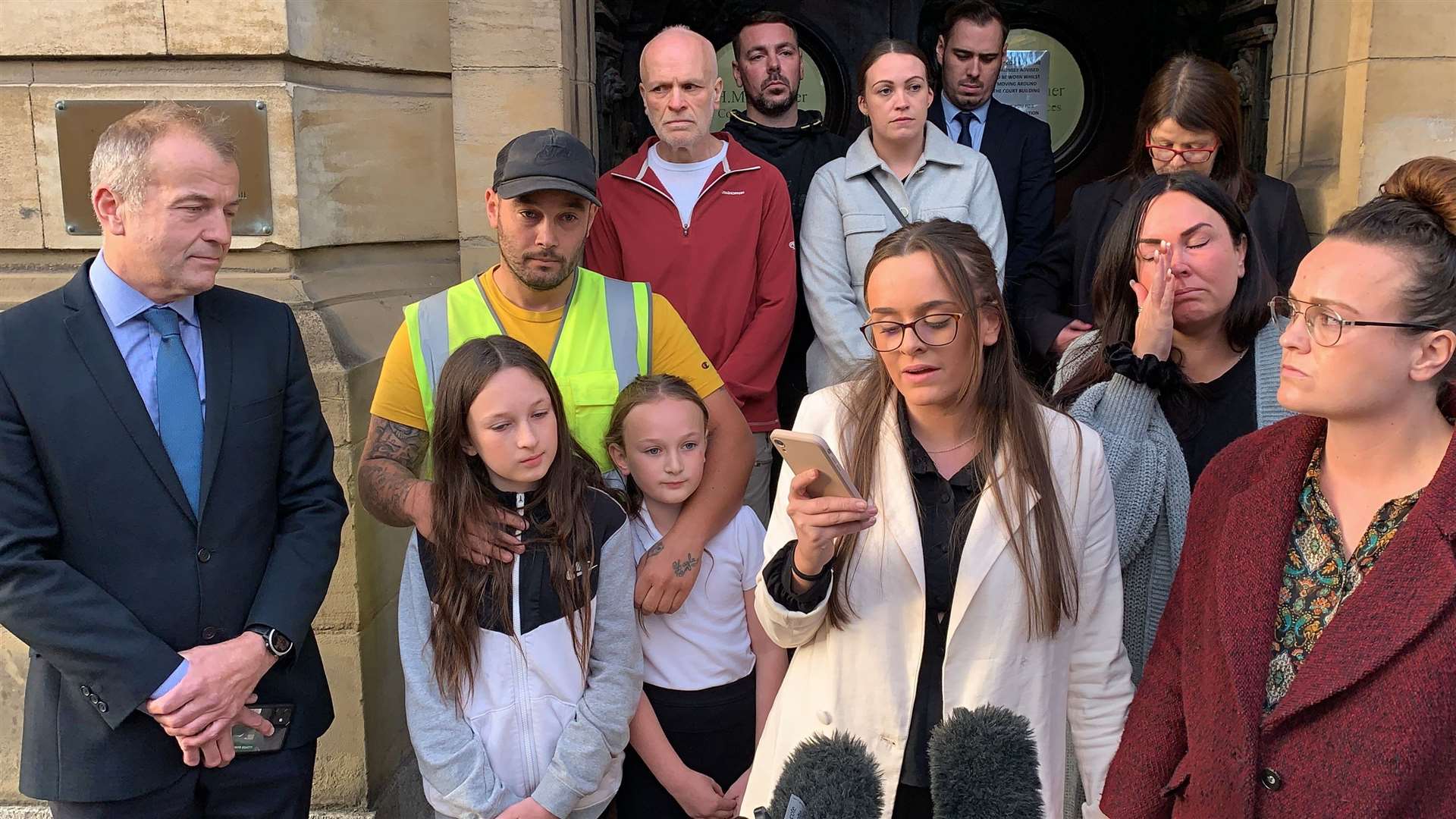 Tia Skelton, centre, the sister of Lewis Skelton, is surrounded by members of their family and solicitor Neil Hudgell, left, as she reads a statement to the media outside Hull Coroner’s Court (Dave Higgens/PA)