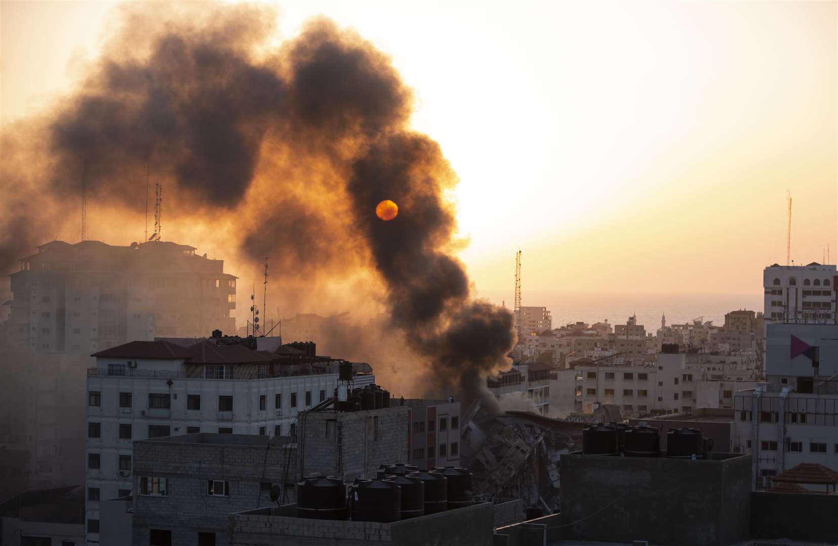 Smoke rises from a collapsed building hit by Israeli air strikes on Gaza City (Khalil Hamra/AP)