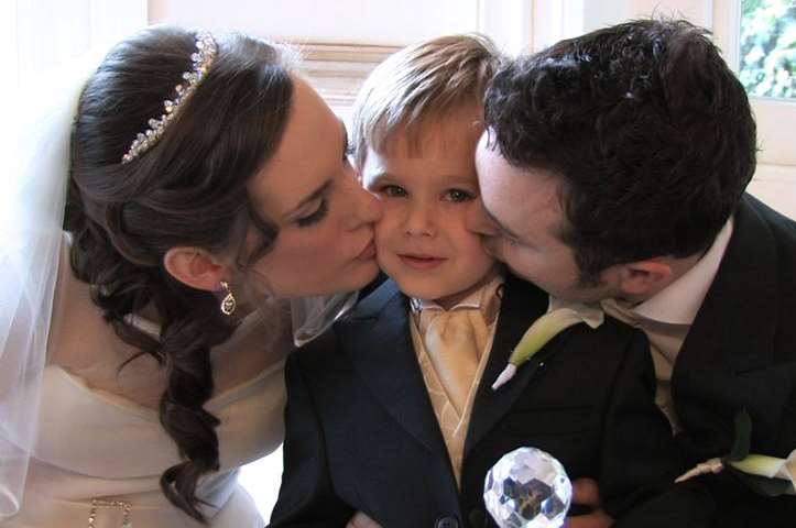 Newly-married couple Ben and Laura Hymas kiss four-year-old Jacob at their wedding