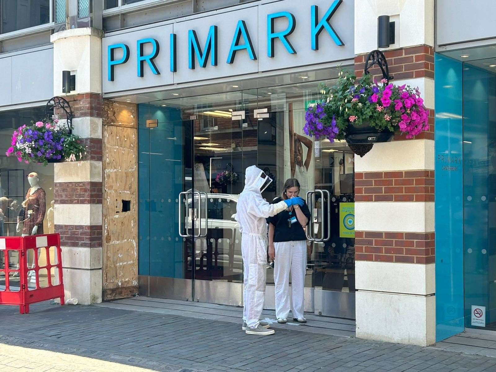 A beekeeper outside Primark in Canterbury which has been evacuated after a swarm of bees clustered around a hanging basket