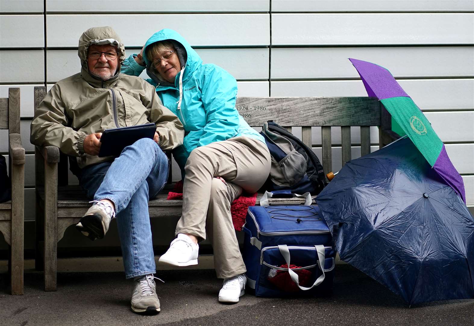 Spectators shield themselves from the rain as play is delayed during day three of the first LV= Insurance Test match at Lord’s (Adam Davy/PA)