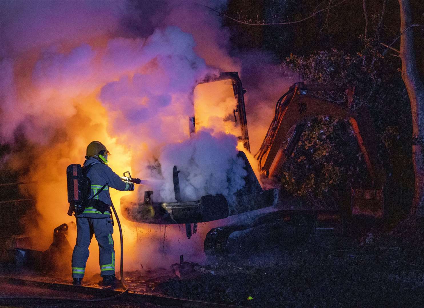 A member of the Northern Ireland Fire and Rescue Service extinguishes a digger which was set alight close to the loyalist Nelson Drive Estate in Londonderry (Liam McBurney/PA)