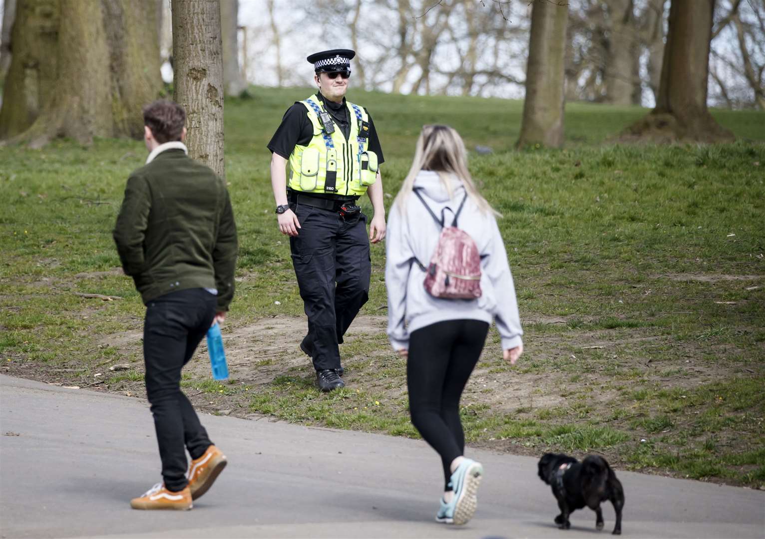 A policeman walks past a people exercising with a dog in Roundhay Park, Leeds (Danny Lawson/PA)