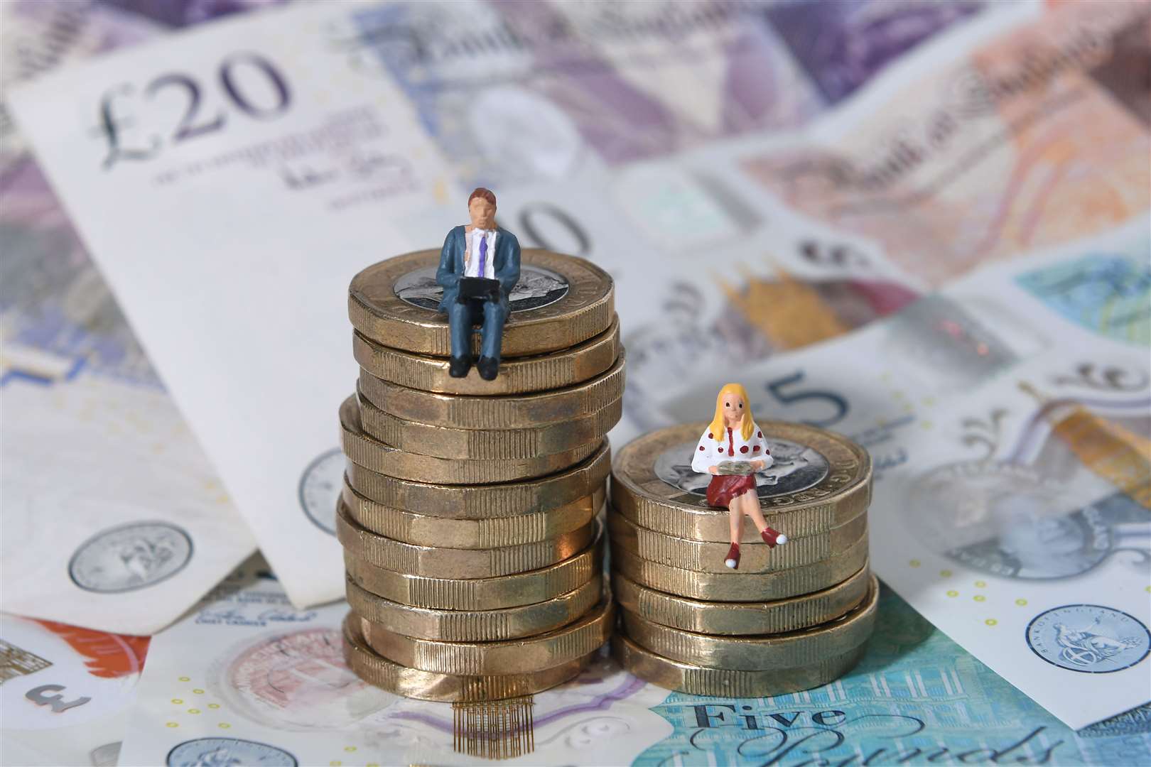 Models of a man and woman stand on a pile of coins and bank notes illustrating a gender pay gap (Joe Giddens/PA)