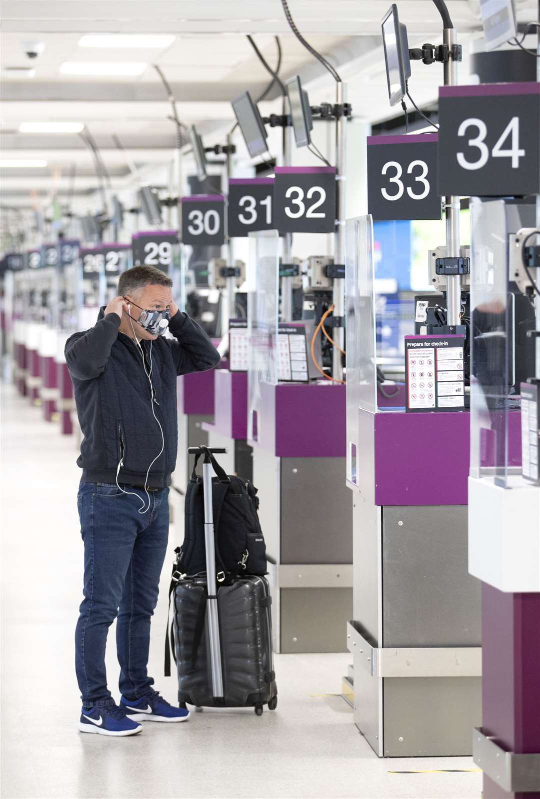 A passenger puts on a protective face mask in the check-in area at Edinburgh Airport (Jane Barlow/PA)