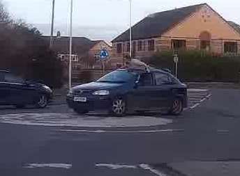 The car surfer can be seen on the car's roof as it travels around a roundabout. Picture: Billy Dempsey.