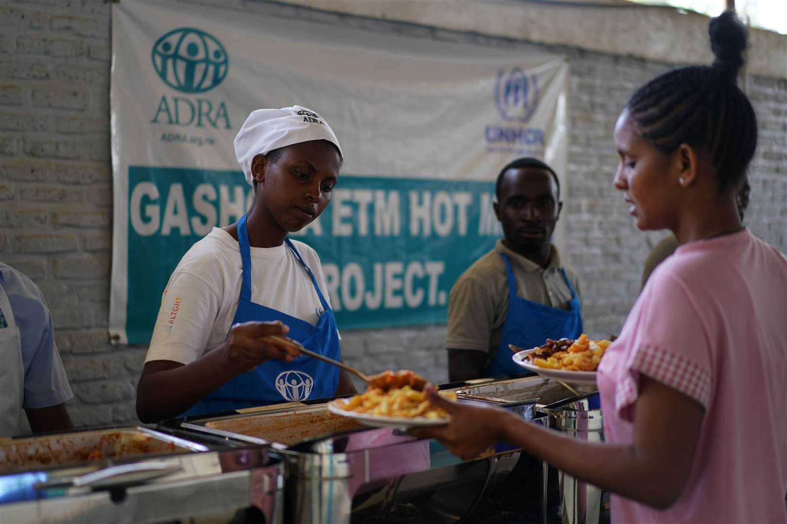 A kitchen worker serves food to a resident in the canteen (Victoria Jones/PA)