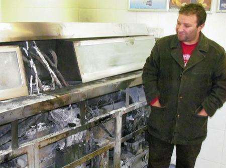 Ossie Altun inspects the damage to his fryers after Sunday's fire at Ossie's Fish Bar in Preston Street