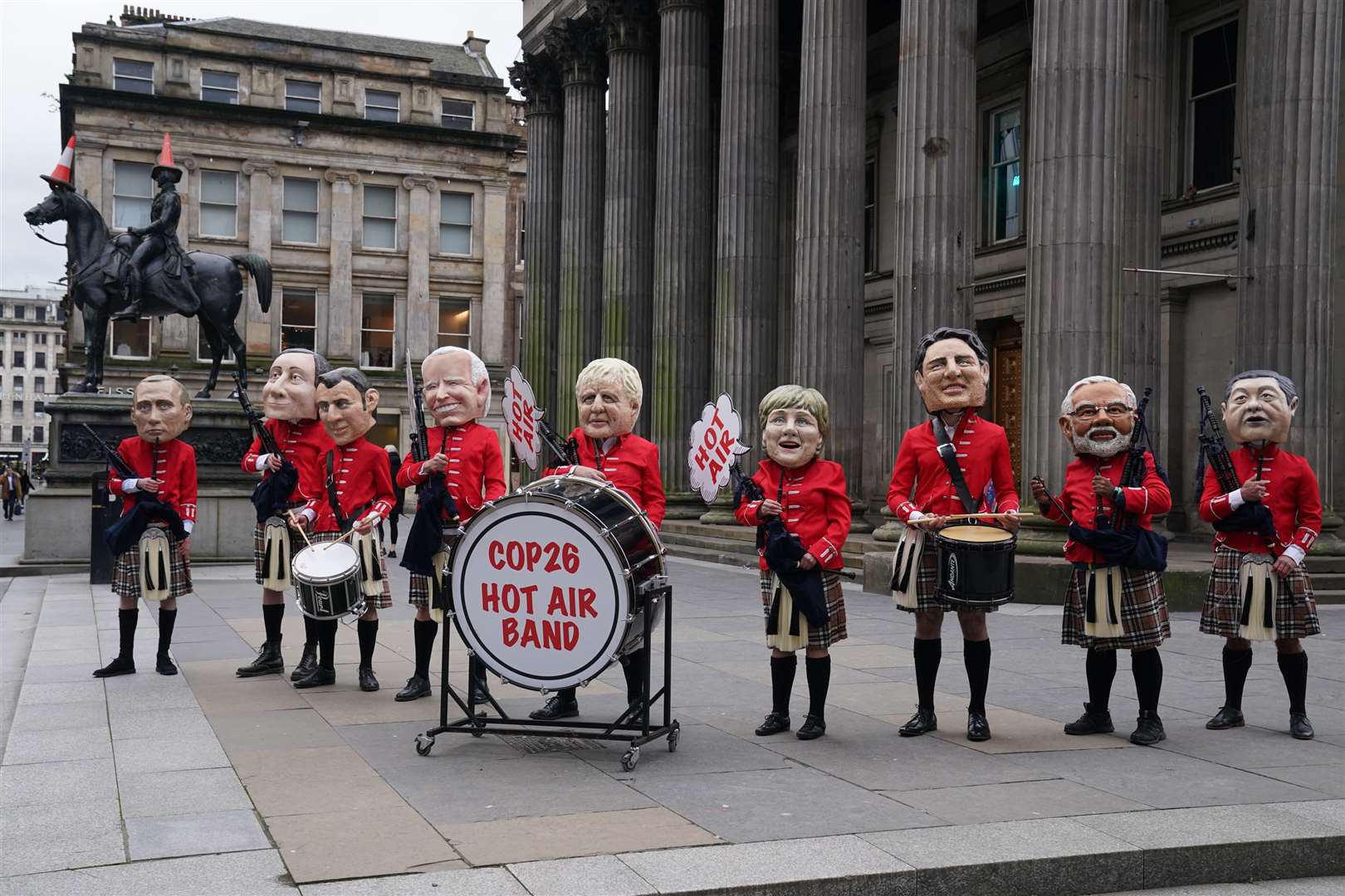 Environmental campaigners with ‘big head’ masks of key world leaders, dressed in kilts and with bagpipes gather in Royal Exchange Square, Glasgow (Owen Humphreys/PA)