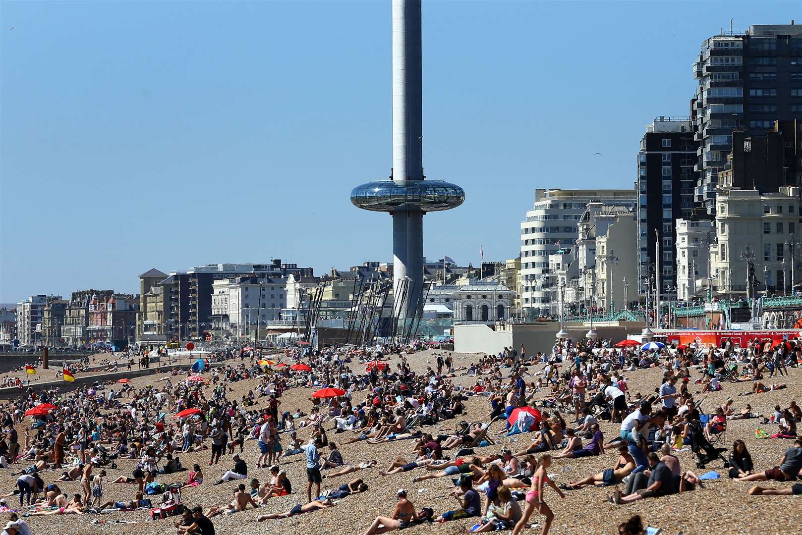 The Brighton i360 rises as people enjoy the warm weather on the beach in Brighton, East Sussex, in 2016 (Gareth Fuller/PA)