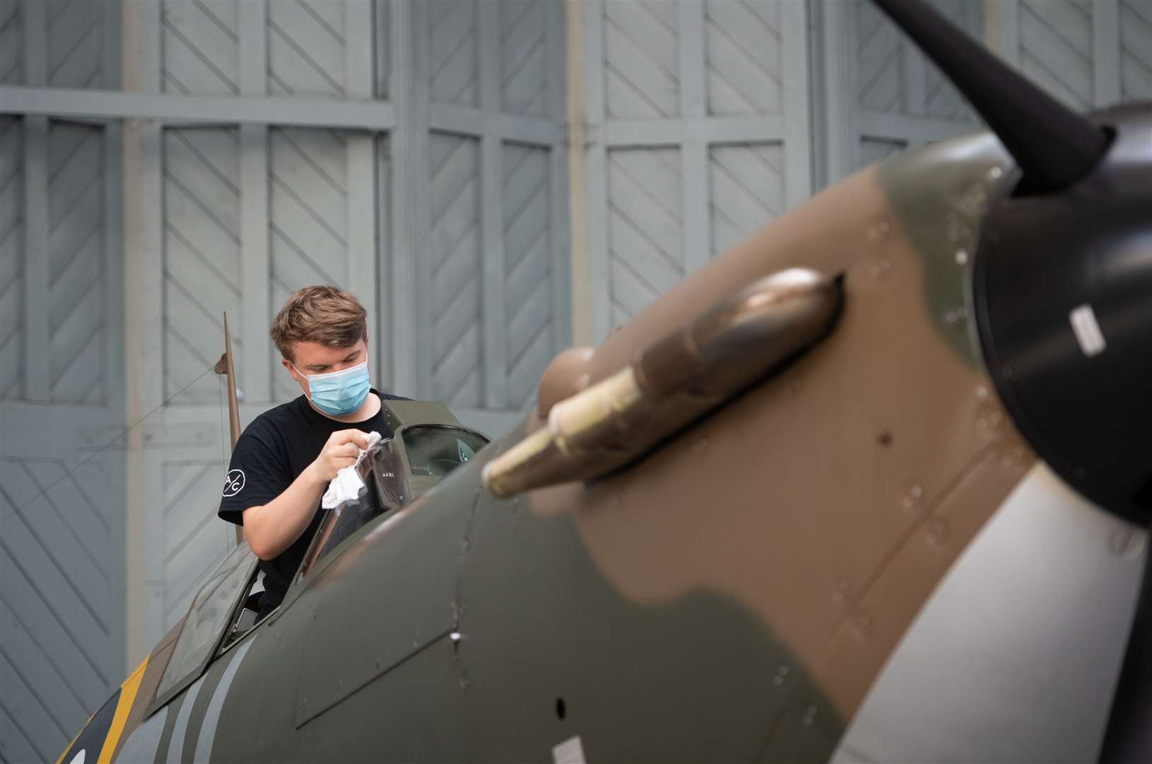 Engineer Joe Malkin from the Aircraft Restoration Company cleans the canopy of a Supermarine Spitfire (Joe Giddens/PA)