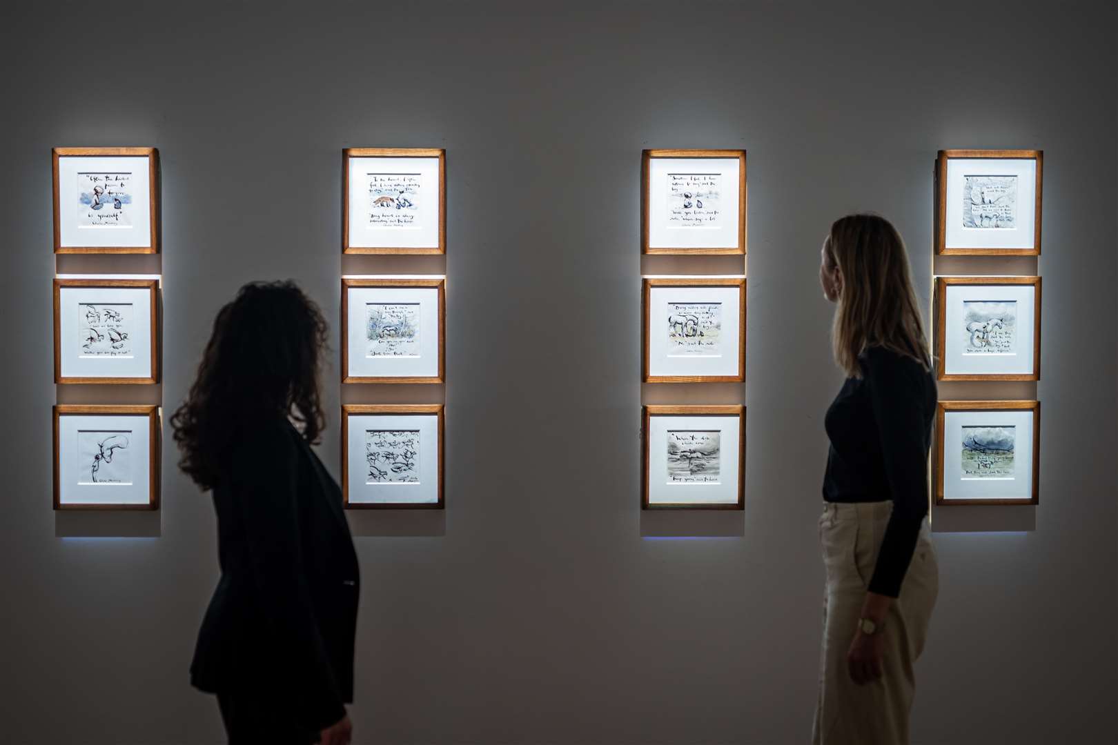 Gallery assistants look at artwork featuring in the ‘Look How Far We’ve Come’ exhibition by Charlie Mackesy at Sotheby’s in London (Aaron Chown/PA)