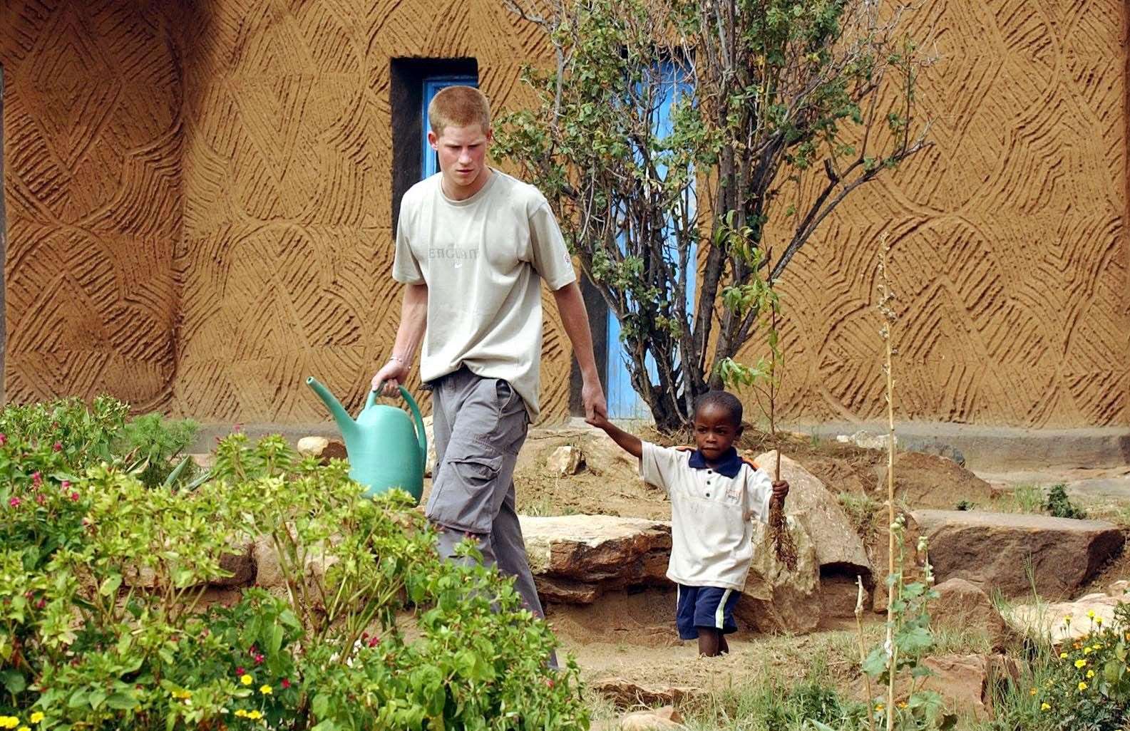 Harry leading young orphan Mutsu Potsane, four, by the hand to plant a peach tree together at the Mants’ase Children’s Home near Mohale’s Hoek (John Stillwell/PA)