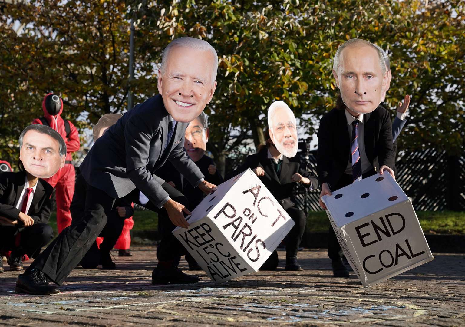 The Glasgow Actions Team, wearing masks depicting Joe Biden and Vladimir Putin, play dice at the Clyde Arc Bridge (Andrew Milligan/PA)