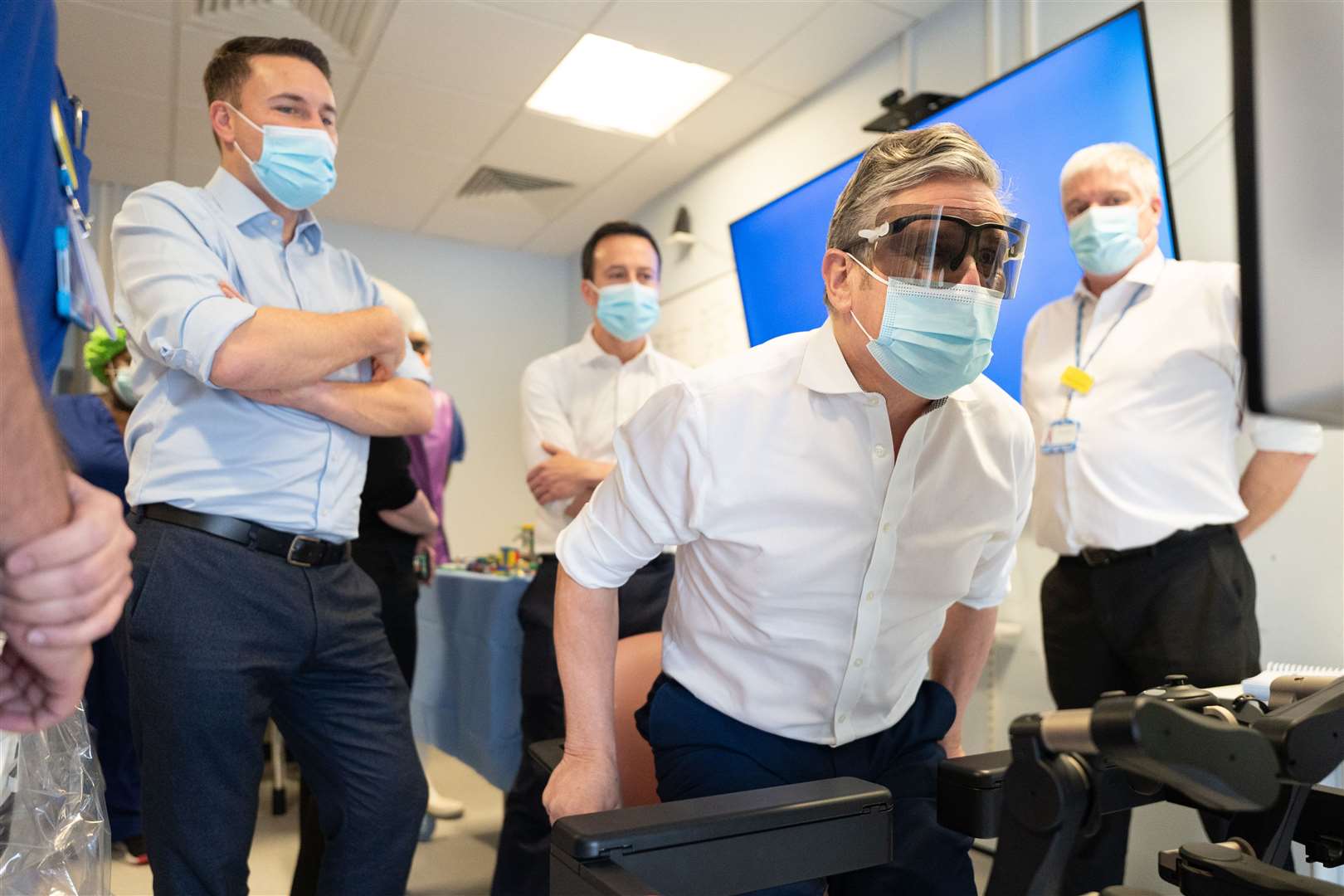 Wes Streeting (left) watches Labour leader Sir Keir Starmer (sitting) tries his hand at operating a surgical procedures robot at the Lister Hospital in Stevenage (Stefan Rousseau/PA)