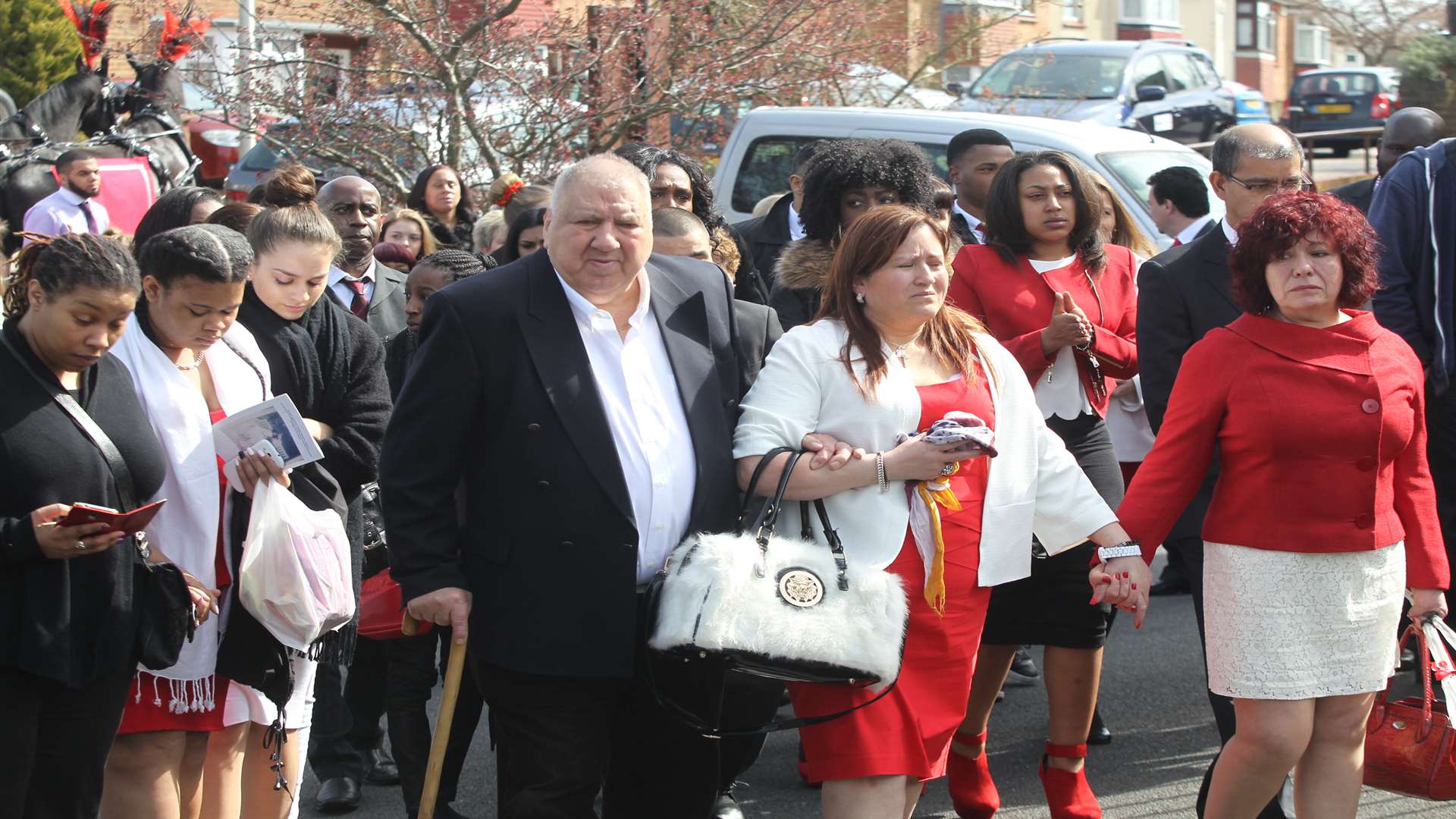 Francesca Thompson, dressed in red and white follows the coffin of her daughter, Monique Bryan who died at the age of 13 of leukaemia arrives at St Justus Church in Rochester.